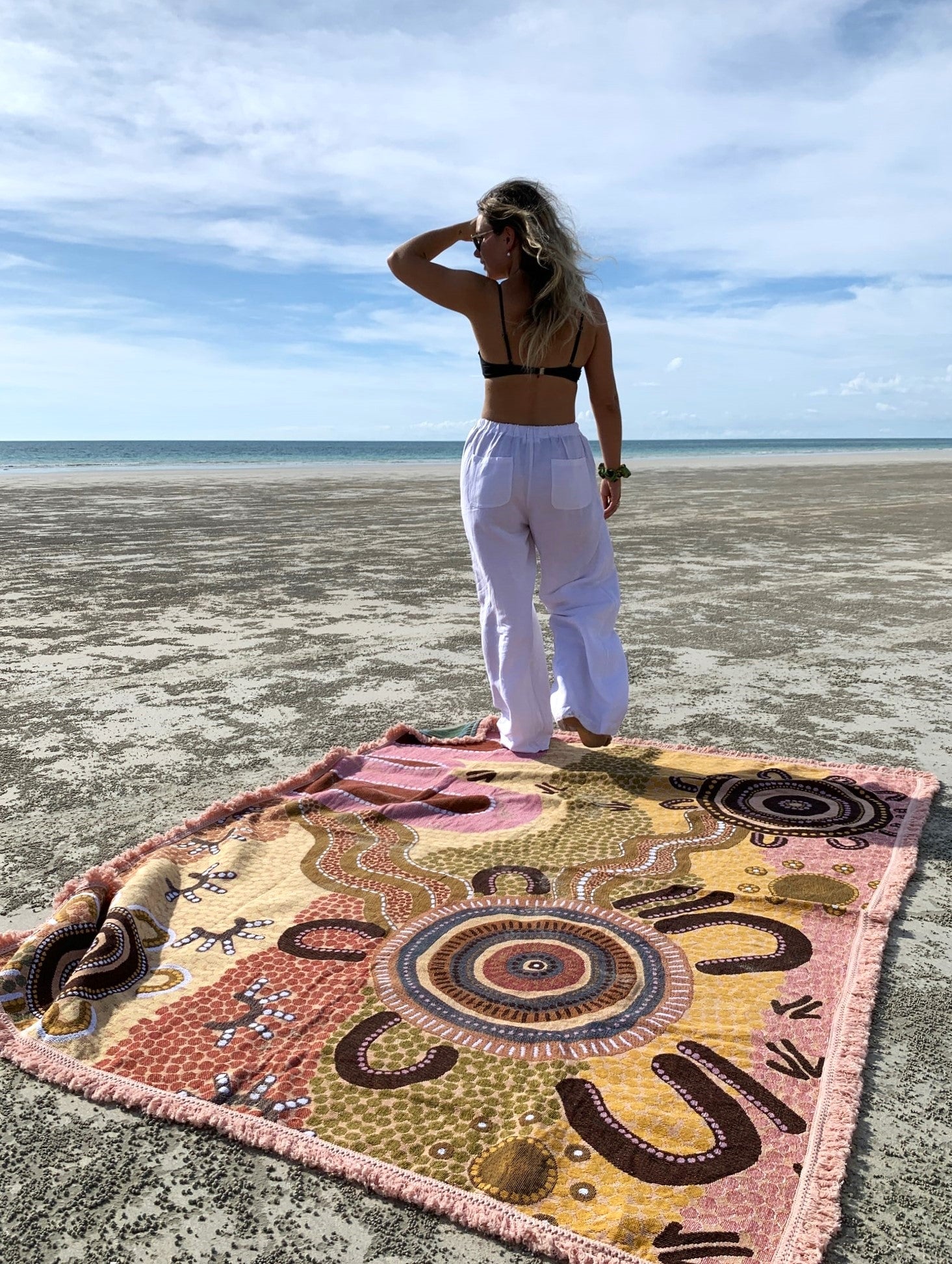 Coming Home Indigenous First Nations art throw rug on beach in Western Australia. Van life. Woven from recycled fabrics. First Nations art, Kalkadoon, designed in Australia