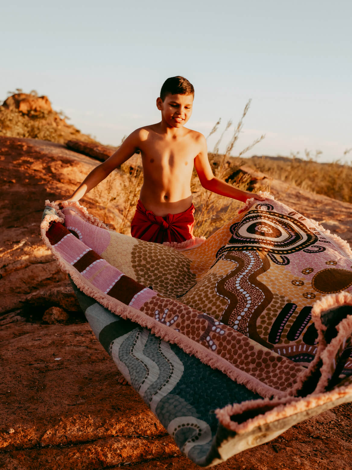 Coming Home Indigenous First Nations art throw rug with Kalkadoon child on Kalkadoon land. Woven from recycled fabrics. First Nations art, Kalkadoon mob designed in Australia