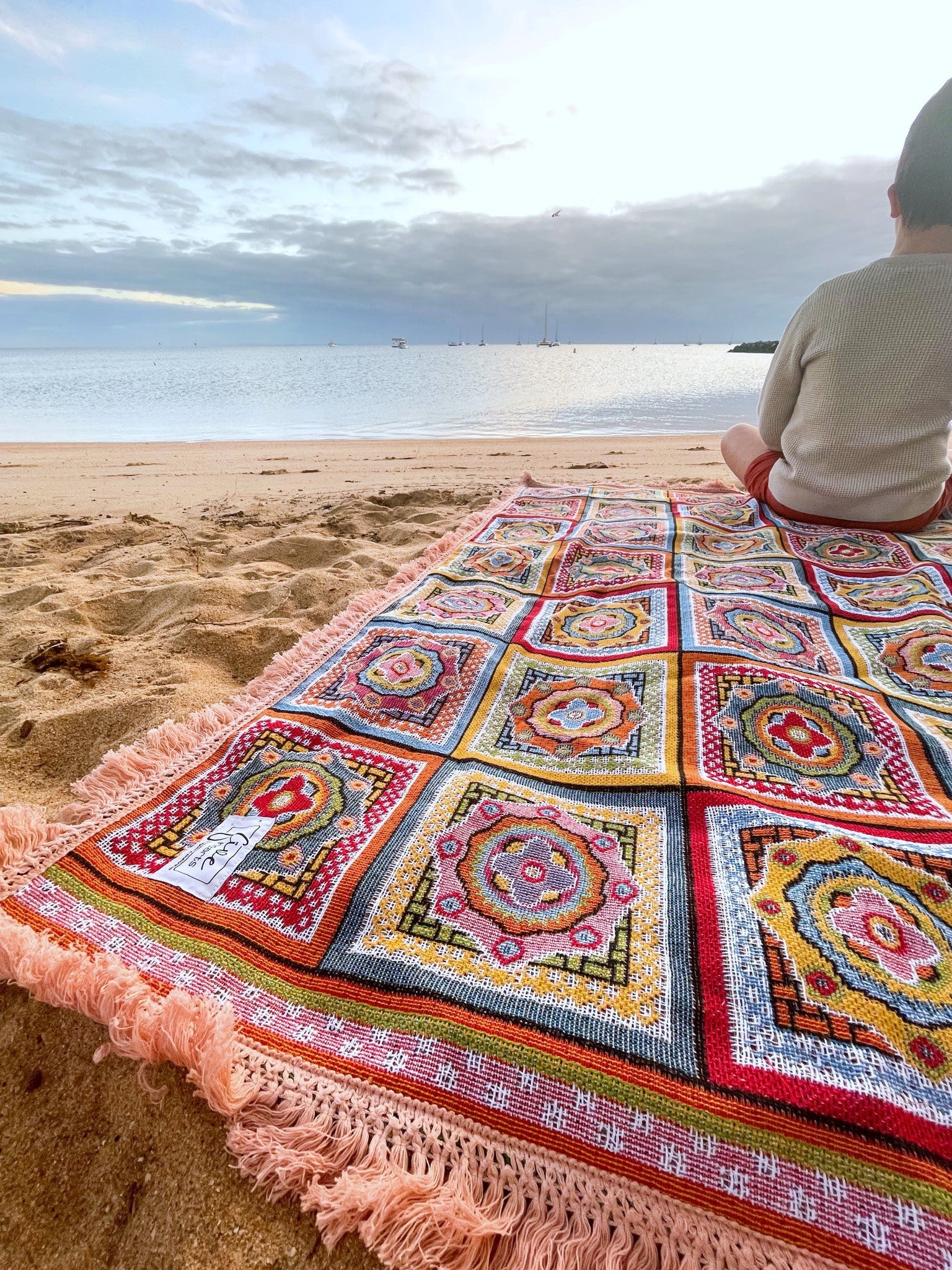 Forever Young Throw Rug laid on beach looking out to the bay off the coast of Brisbane.