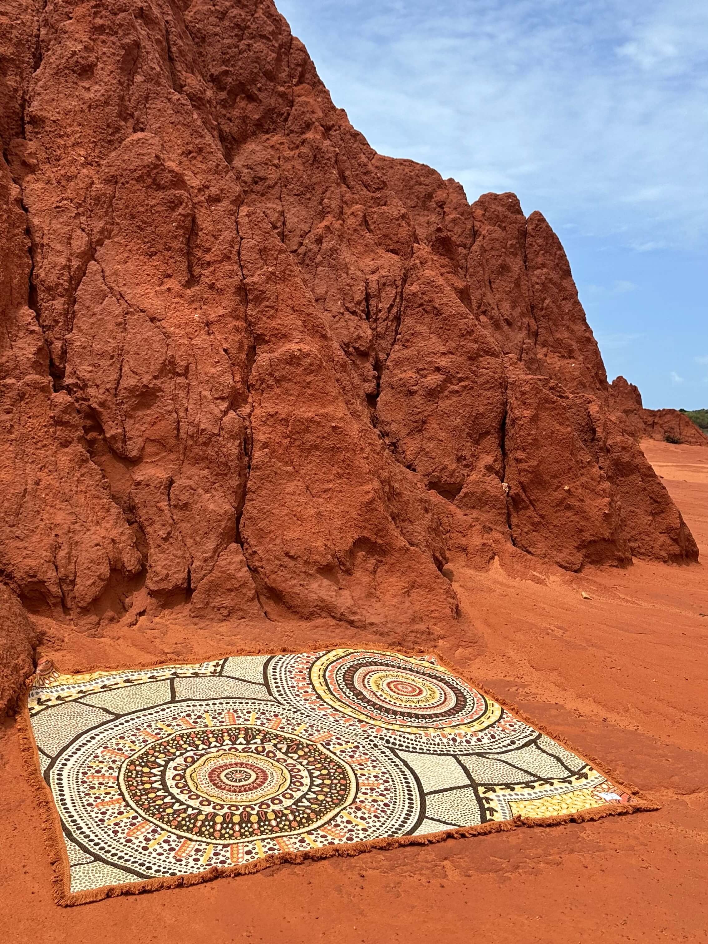 Stomping Ground Indigenous design throw rug laying on rich red dirt