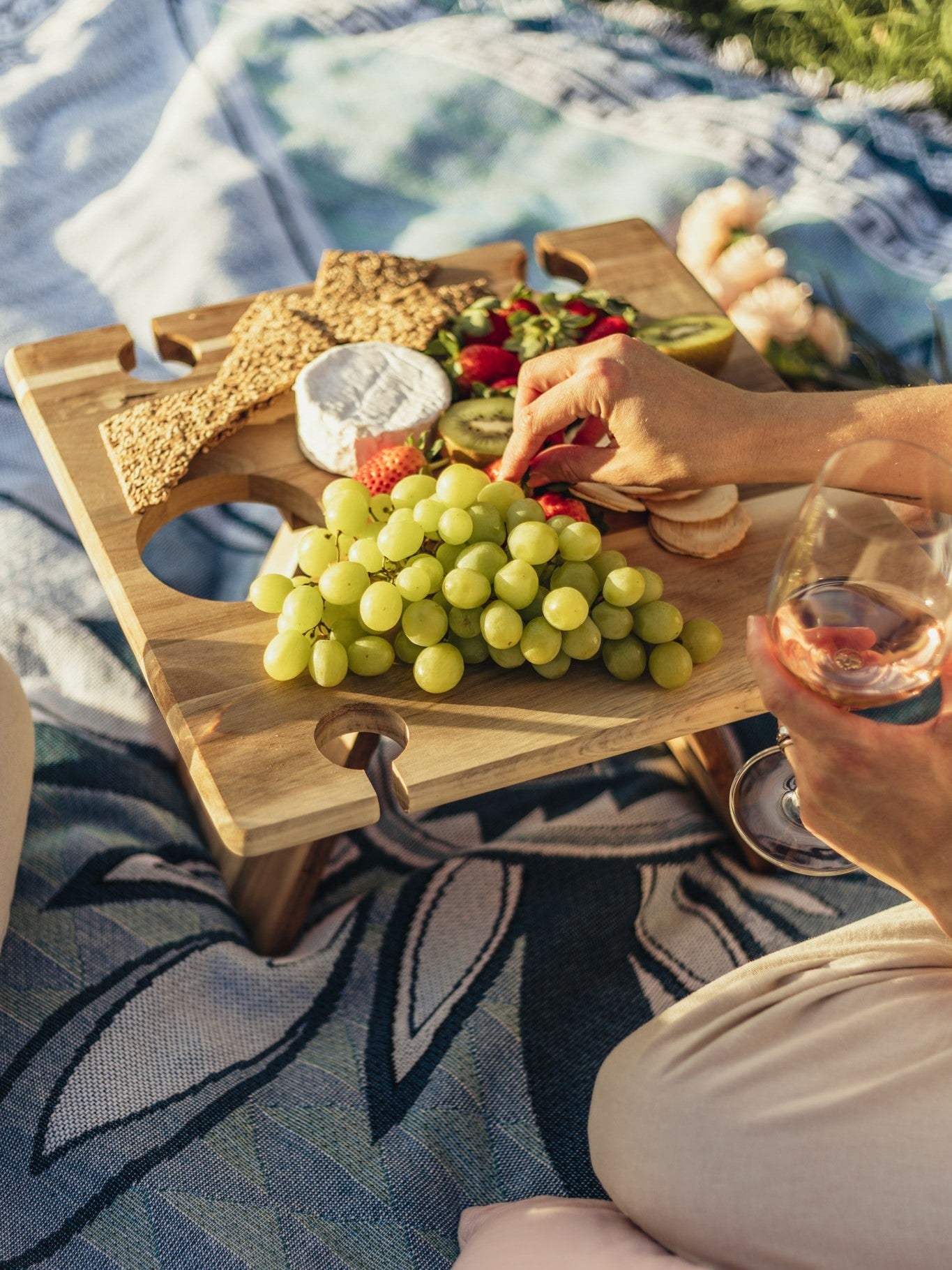 Shooting Stars blue throw rug, picnic blanket laying on grass overlooking sunset. Designed in Aus.