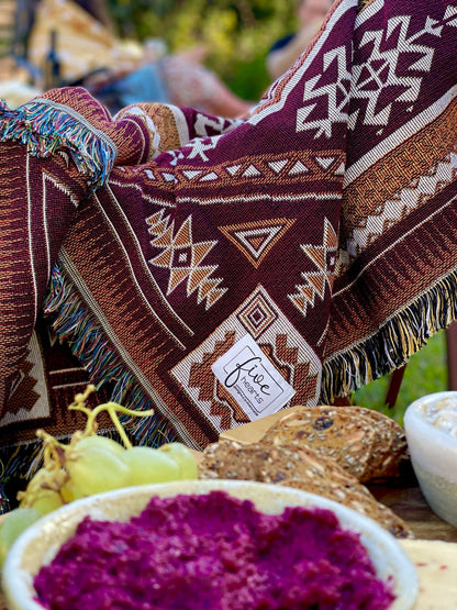 Desert Night throw rug and picnic blanket over camping chair with nibbles. Shades of brown, boho rug, must-have van life accessory. Designed in Australia for adventure.