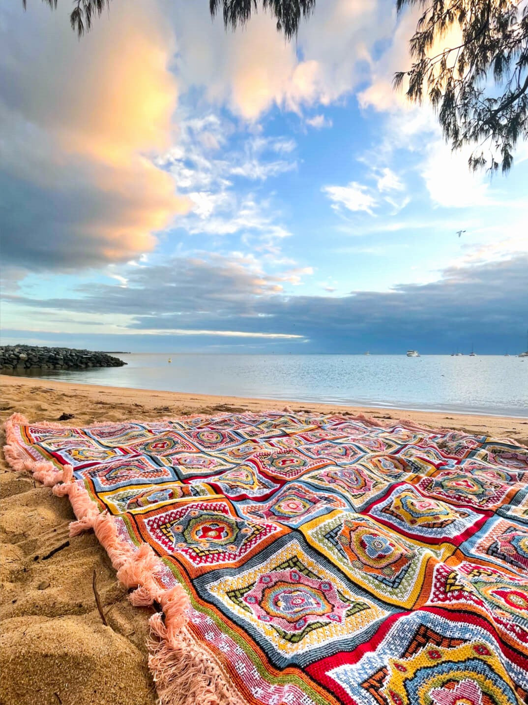 Forever Young Throw Rug laid on a beach overlooking the ocean at sunrise